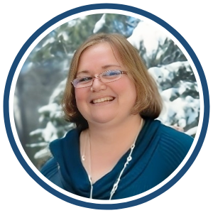 A circular headshot of a smiling woman with short, light brown hair, wearing glasses and a teal top with a draped neckline. She is also wearing a silver necklace. The background features a snowy, winter landscape with snow-covered trees, and a dark blue border surrounds the image.